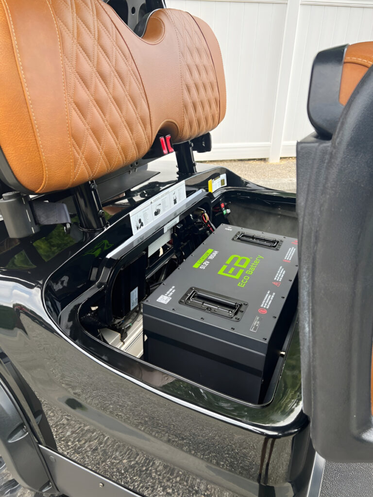 Lithium battery installed under the lifted seat of a black golf cart
